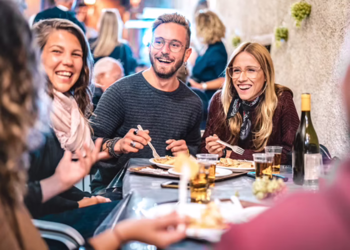 A group of people laughing while sat in a restaurant.
